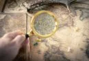 An image of a person's hand holding a magnifying glass, examining a map with various symbols and markings, representing the exploration and understanding of different types of illegal trades.