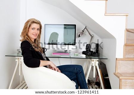 Young professional seated at her workstation at home.